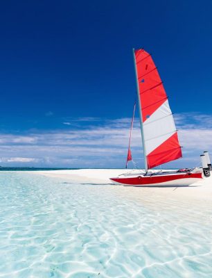 sailing-boat-with-red-sail-on-a-beach-of-deserted-1536x1024